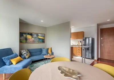 a living room with a blue couch and a table at Affinity ApartaHotel - Extended Stay in Medellín