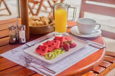 a plate of fruit on a table with a glass of orange juice at Leblon Suites Hotel Milla de Oro in Medellín