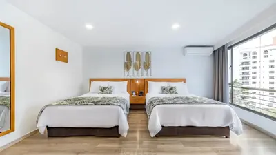 two beds in a white room with a window at Leblon Suites Hotel Milla de Oro in Medellín