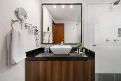 a bathroom with a sink and a mirror and a shower at Leblon Suites Hotel Milla de Oro in Medellín