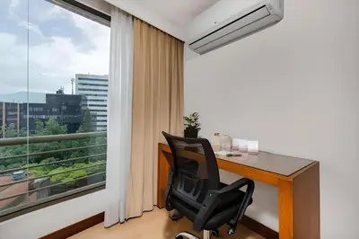 an office with a desk and a chair in front of a window at Leblon Suites Hotel Milla de Oro in Medellín