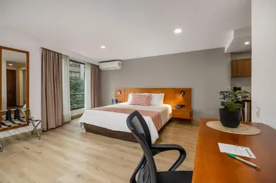 a hotel room with a bed and a desk at Leblon Suites Hotel Milla de Oro in Medellín