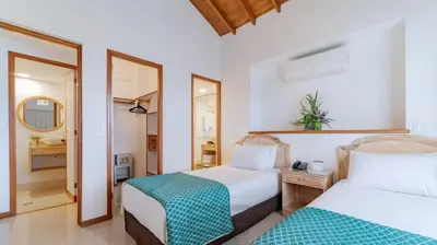 a bedroom with two beds and a mirror at Portal del Rodeo ApartaHotel - Arkadia Mall in Medellín