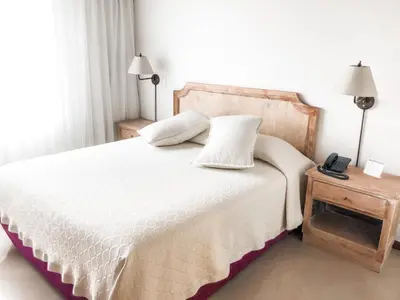 a bedroom with a white bed with a phone on a table at Portal del Rodeo ApartaHotel - Arkadia Mall in Medellín