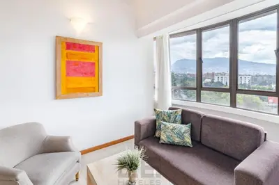 a living room with a couch and two chairs and a window at Portal del Rodeo ApartaHotel - Arkadia Mall in Medellín