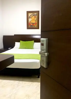 a bedroom with two beds with a green pillow at Hotel Palma 70 in Medellín