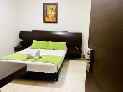 a bedroom with a bed with green and white sheets at Hotel Palma 70 in Medellín
