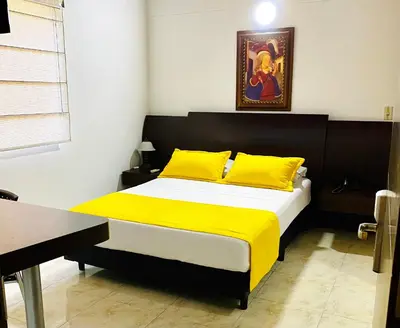 a bedroom with a large bed with yellow pillows at Hotel Palma 70 in Medellín