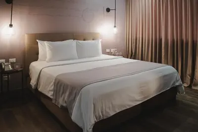 a bedroom with a large bed with white sheets and pillows at Sites Hotel in Medellín