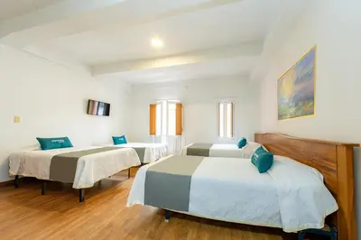 a room with two beds and a table at Ayenda Escorial 1936 in Manizales