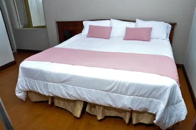 a large bed with two pink pillows on it at Ayenda Escorial 1936 in Manizales