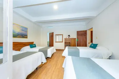 a hotel room with three beds in it at Ayenda Escorial 1936 in Manizales