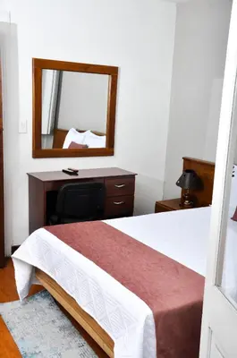 a bedroom with a bed with a desk and a mirror at Ayenda Escorial 1936 in Manizales