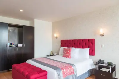 a bedroom with a large bed with a red headboard at Hotel Varuna in Manizales