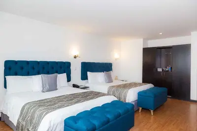 a hotel room with two beds and a blue couch at Hotel Varuna in Manizales