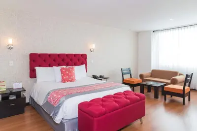 a bedroom with a large red bed and a red couch at Hotel Varuna in Manizales