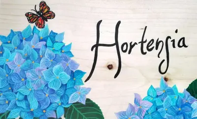 a sign with blue flowers and a butterfly on it at 40 Amigos Hotel in Jardin