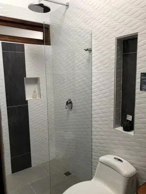 a bathroom with a glass shower with a toilet at 40 Amigos Hotel in Jardin