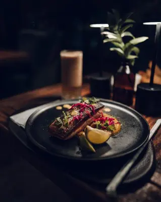 a black plate with food on a wooden table at Bosko in Guatapé