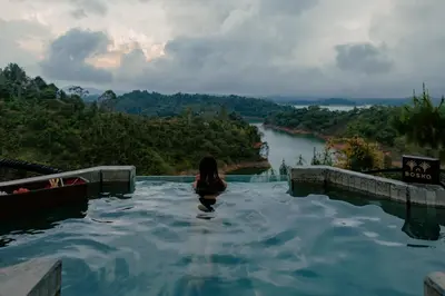 a woman sitting in a hot tub overlooking a river at Bosko in Guatapé