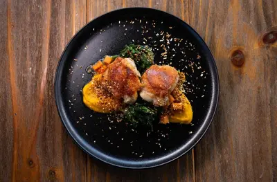 a black plate with food on a wooden table at Bosko in Guatapé