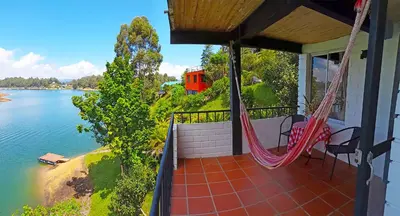 a porch with a hammock and a view of the water at Ecolodge Bahia del Peñón in Guatapé