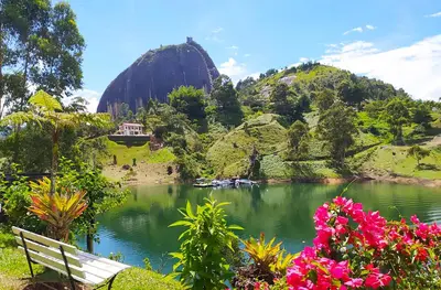 a bench next to a lake with a mountain at Ecolodge Bahia del Peñón in Guatapé
