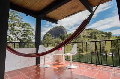 a balcony with a hammock and a view of a mountain at Ecolodge Bahia del Peñón in Guatapé