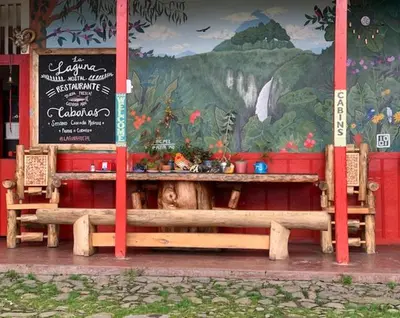 a table and benches in front of a restaurant at Hostal La Laguna in Villamaría