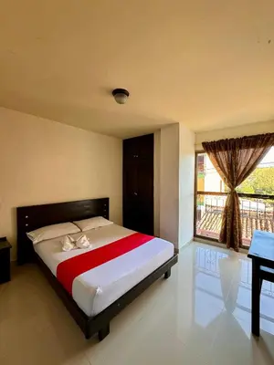 a bedroom with a bed and a window and a desk at Hotel Portal Dorado in Marinilla