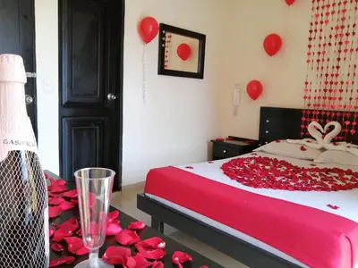 a bedroom with a bed with red roses and balloons at Hotel Portal Dorado in Marinilla