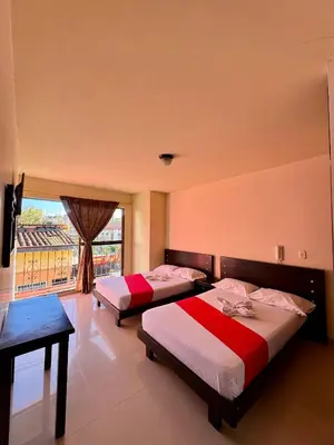 two beds in a room with a large window at Hotel Portal Dorado in Marinilla
