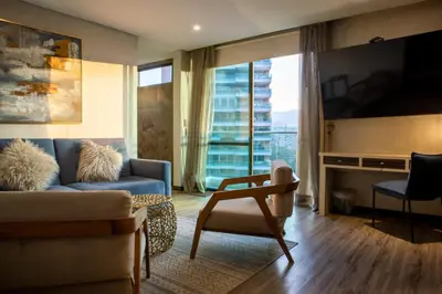 a living room with a couch and a tv at Cafe Hotel Medellín in Medellín