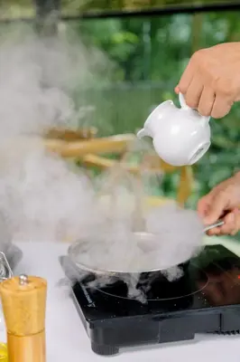 a person holding a teapot over a pot on a stove at Cafe Hotel Medellín in Medellín