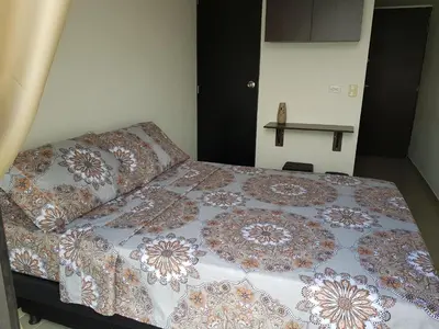 a bed with a quilt on it in a bedroom at Apartasuites Medellin Los Molinos in Medellín
