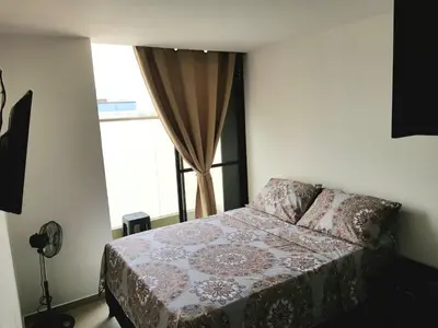 a bedroom with a bed and a window at Apartasuites Medellin Los Molinos in Medellín