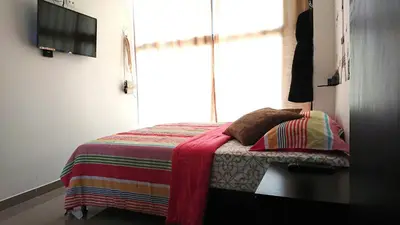 a small bedroom with a bed with a window at Apartasuites Medellin Los Molinos in Medellín