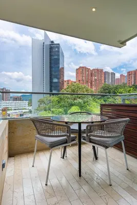 a balcony with a glass table and two chairs at Estelar La Torre Suites in Medellín