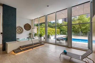 an empty living room with a pool seen through the windows at Estelar La Torre Suites in Medellín