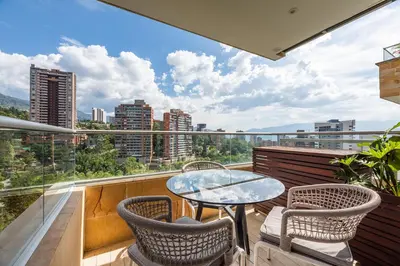 a balcony with a glass table and chairs at Estelar La Torre Suites in Medellín