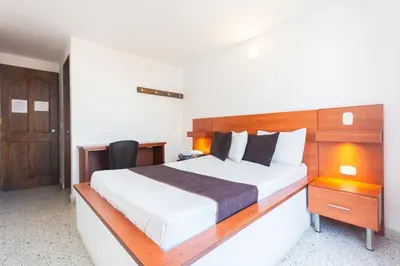 a bedroom with a large bed with a wooden headboard at Hotel Bicentenario Rionegro in Rionegro