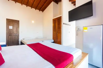 a bedroom with a white bed and a flat screen tv at Hotel Bicentenario Rionegro in Rionegro