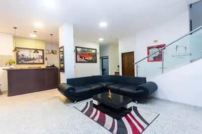 a living room with a black couch and a staircase at Hotel Bicentenario Rionegro in Rionegro
