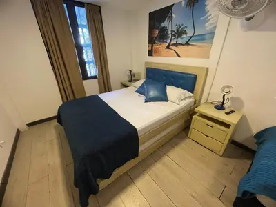 a bedroom with a bed with a blue headboard and a window at Air Guest House - con Desayuno & Jacuzzi Social in Medellín