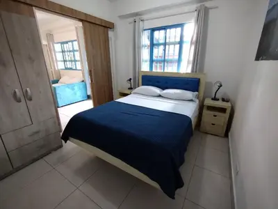 a bedroom with a bed with a blue blanket and two windows at Air Guest House - con Desayuno & Jacuzzi Social in Medellín