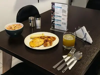 a table with a plate of food and a glass of orange juice at Air Guest House - con Desayuno & Jacuzzi Social in Medellín