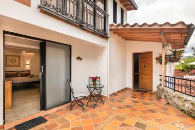a patio with a table and a room with a bed at Serendipity Hospedaje Boutique in Guatapé