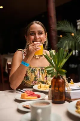 a woman sitting at a table drinking a glass of orange juice at Hotel Quimbaya in San Jerónimo