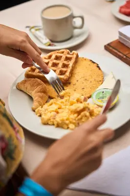 a person eating a breakfast plate of eggs and waffles at Hotel Quimbaya in San Jerónimo