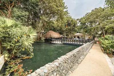 a river with a stone wall next to a house at Hotel Quimbaya in San Jerónimo